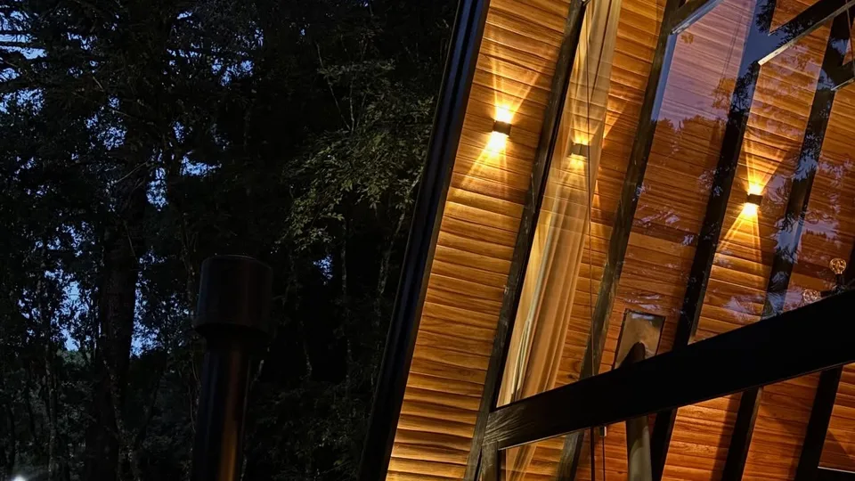 A cabana iluminada à noite, com a luz quente atrás do vidro